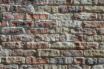 View of old shabby wall made from multicolored bricks. Abstract textured background. Copy space for your text and decorations.