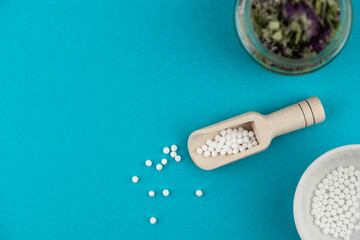 Homeopathy alternative medicine eco concept - classical homeopathy pills. Homeopathic globules and healing herbs. Blue background. 