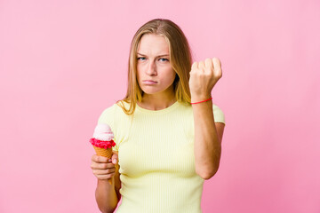 Young russian woman eating an ice cream isolated showing fist to camera, aggressive facial expression.