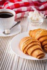 delicious fresh croissant and cup of coffee on a white wooden rustic background