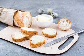 Tasty breakfast. Fresh baguette sandwiches with butter and quail eggs on a cutting board on the...