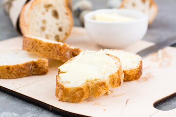 Delicious breakfast in the morning. Fresh baguette sandwiches with butter on a cutting board on the table