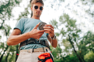 Male hiker in bright summer clothes stands in the woods with a skein of sling in his hands. Focus on slings in the hands of a man during an active vacation in the wild.