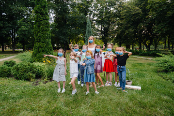 Obraz premium A class of masked school children is engaged in outdoor training during the epidemic. Back to school, learning during the pandemic