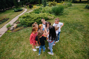 Obraz premium A group of children run around, have fun and play as a larger team in the summer in the Park. Happy childhood