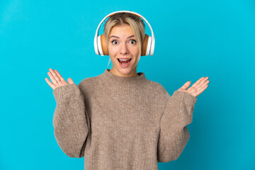 Young Russian woman isolated on blue background surprised and listening music
