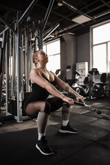 Fototapeta na wymiar Vertical shot of a sportswoman squatting in crossover gym machine