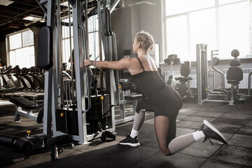 Fototapeta premium Rear view shot of a fitness woman exercising at sports studio