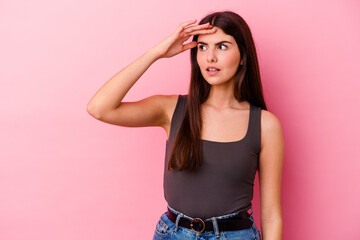 Young caucasian woman isolated on pink background looking far away keeping hand on forehead.