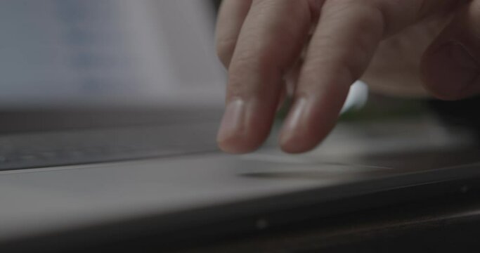 Man worker scrolls page using touchpad on modern laptop