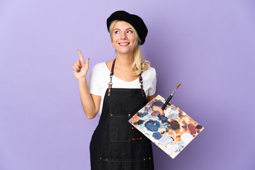 Young artist Russian woman holding a palette isolated on purple background pointing up a great idea