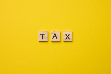 inscription tax on a yellow background from wooden blocks, payment of taxes