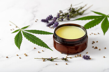 Fototapeta na wymiar Composition with cannabis wax salve or cream with lavender extract and flowers on marble background