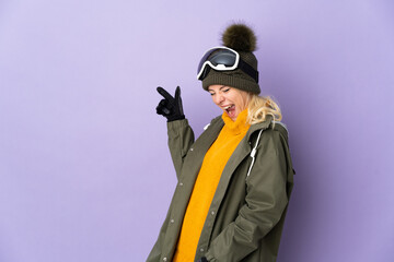 Skier Russian girl with snowboarding glasses isolated on purple background pointing finger to the side and presenting a product