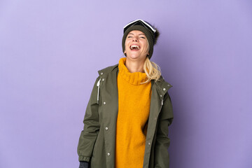 Skier Russian girl with snowboarding glasses isolated on purple background laughing