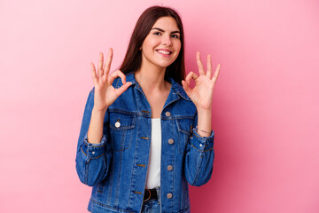 Young caucasian woman isolated on pink background cheerful and confident showing ok gesture.