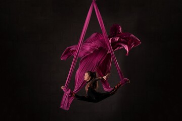 Woman performing acrobatic dance on aerial silks - Powered by Adobe