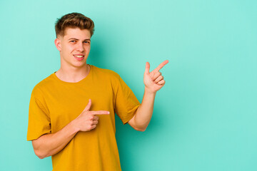 Young caucasian man isolated on blue background excited pointing with forefingers away.