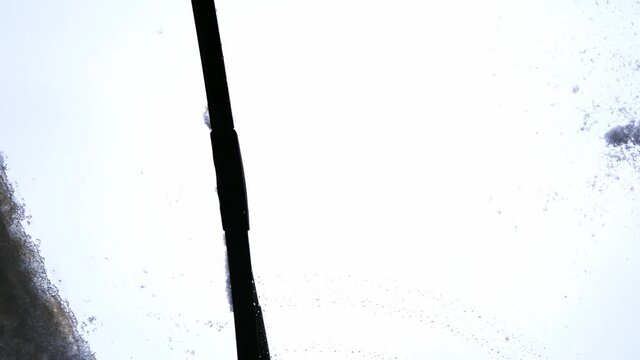 Car wipers clean the windshield from snow. View from inside the cabin, hand-held video shooting