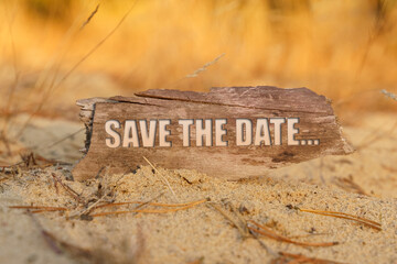In the sand against the background of yellow grass there is a sign with the inscription - SAVE THE DATE