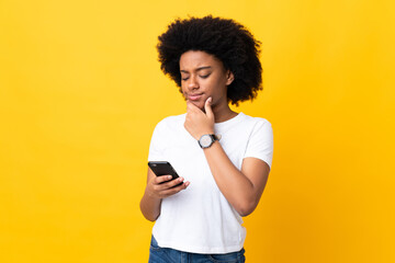 Young African American woman isolated on yellow background thinking and sending a message