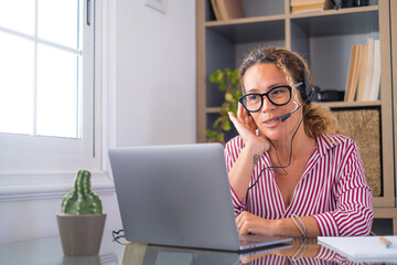 Attractive caucasian woman sit at homeoffice room wearing headset take part in educational webinar...