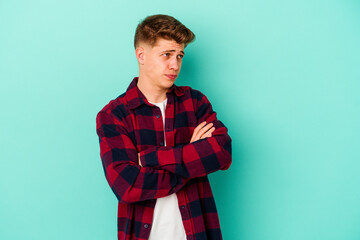 Young caucasian man isolated on blue background dreaming of achieving goals and purposes
