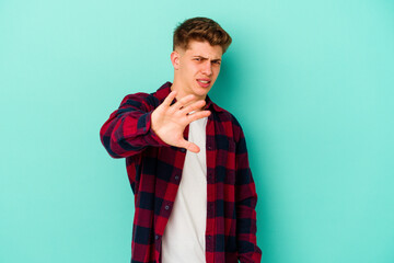 Young caucasian man isolated on blue background rejecting someone showing a gesture of disgust.