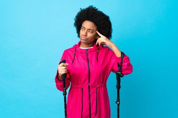 Young Africa American with backpack and trekking poles isolated on blue background making the...