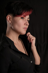 Half-length portrait of pretty young adult brunette isolated on black background looking away, copyspace