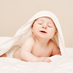 Cute small boy lying at bed. Childhood bath concept. Light background. Little child. Serious calm emotion. Copyspace. Stay home. Towel mockup. Closed eyes