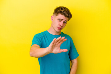 Young caucasian man isolated on yellow background being shocked due to an imminent danger