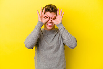 Young caucasian man isolated on yellow background excited keeping ok gesture on eye.