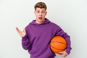 Young caucasian man playing basketball isolated background surprised and shocked.