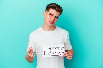 Young caucasian man holding a Holidays placard isolated on blue background