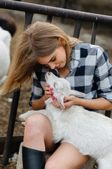 A young pretty girl poses on a ranch with goats and other animals. Agriculture, livestock breeding