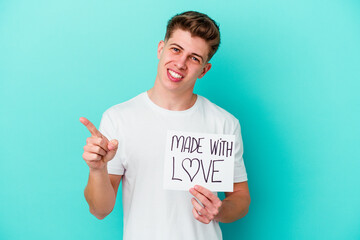 Young caucasian man holding a made with love placard isolated on blue background