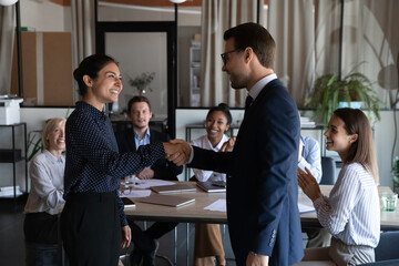 Smiling diverse multiracial employees handshake close deal agreement at meeting. Happy multiethnic...