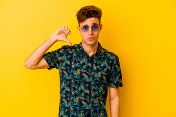 Young caucasian man wearing a Hawaiian shirt isolated on yellow background showing a dislike gesture, thumbs down. Disagreement concept.