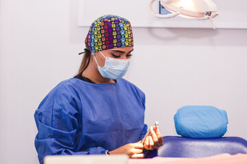 A portrait of a female dentist in her clinic with safety clothing amd mask. Retrato de una dentista...