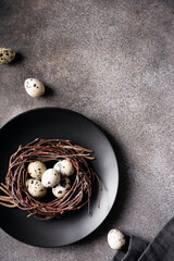 Easter sawn eggs in a nest on a dark concrete background in a black plate, vertical orientation, copy space, close-up