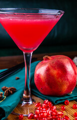 Pomegranate cocktail in martini glass on wooden table. Close up