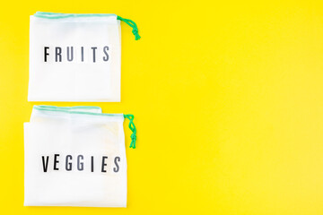 Reusable bags for fruits and vegetables on yellow background, zero waste or plastic free concept, horizontal, top view, copy space
