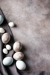 Easter eggs in gray and blue color close up on dark concrete background, vertical orientation, flat lay