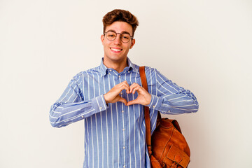 Young student man isolated on white background smiling and showing a heart shape with hands.