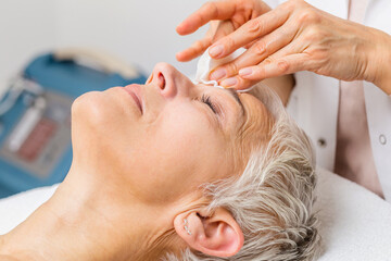 Beautiful senior woman getting spa massage treatment at beauty spa salon. Facial beauty treatment.