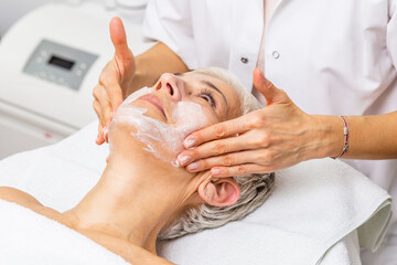 Beautiful senior woman getting spa massage treatment at beauty spa salon. Facial beauty treatment.