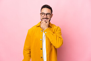 Young caucasian handsome man isolated on pink background looking to the side and smiling