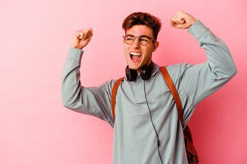 Young student man isolated on pink background raising fist after a victory, winner concept.