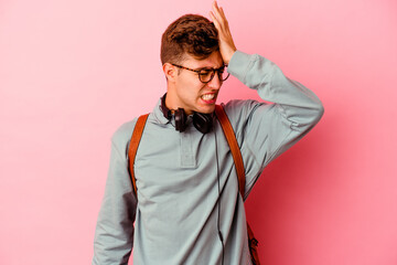 Young student man isolated on pink background forgetting something, slapping forehead with palm and closing eyes.